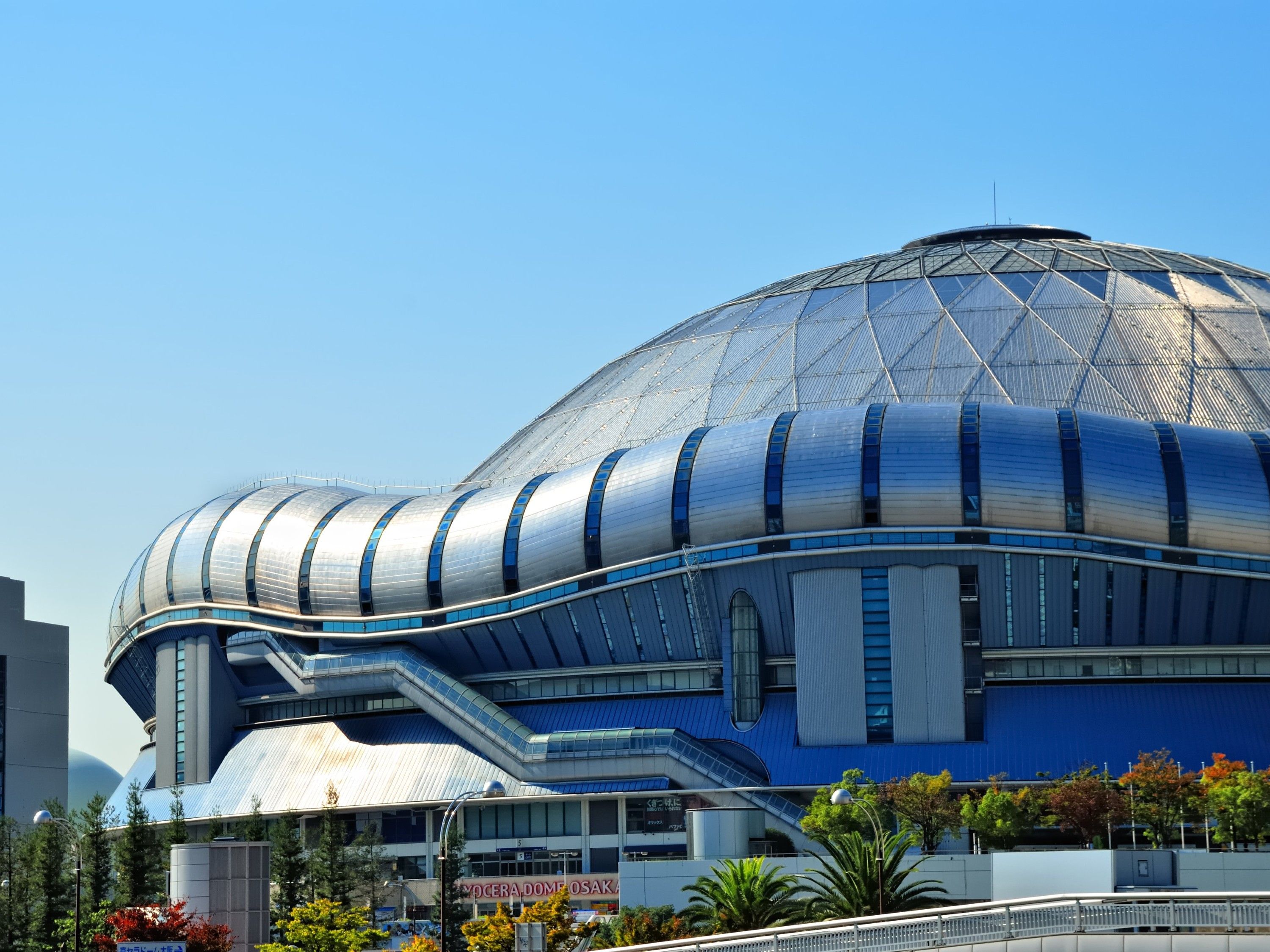Un edificio moderno con fachada metálica curva y una gran estructura en forma de cúpula.