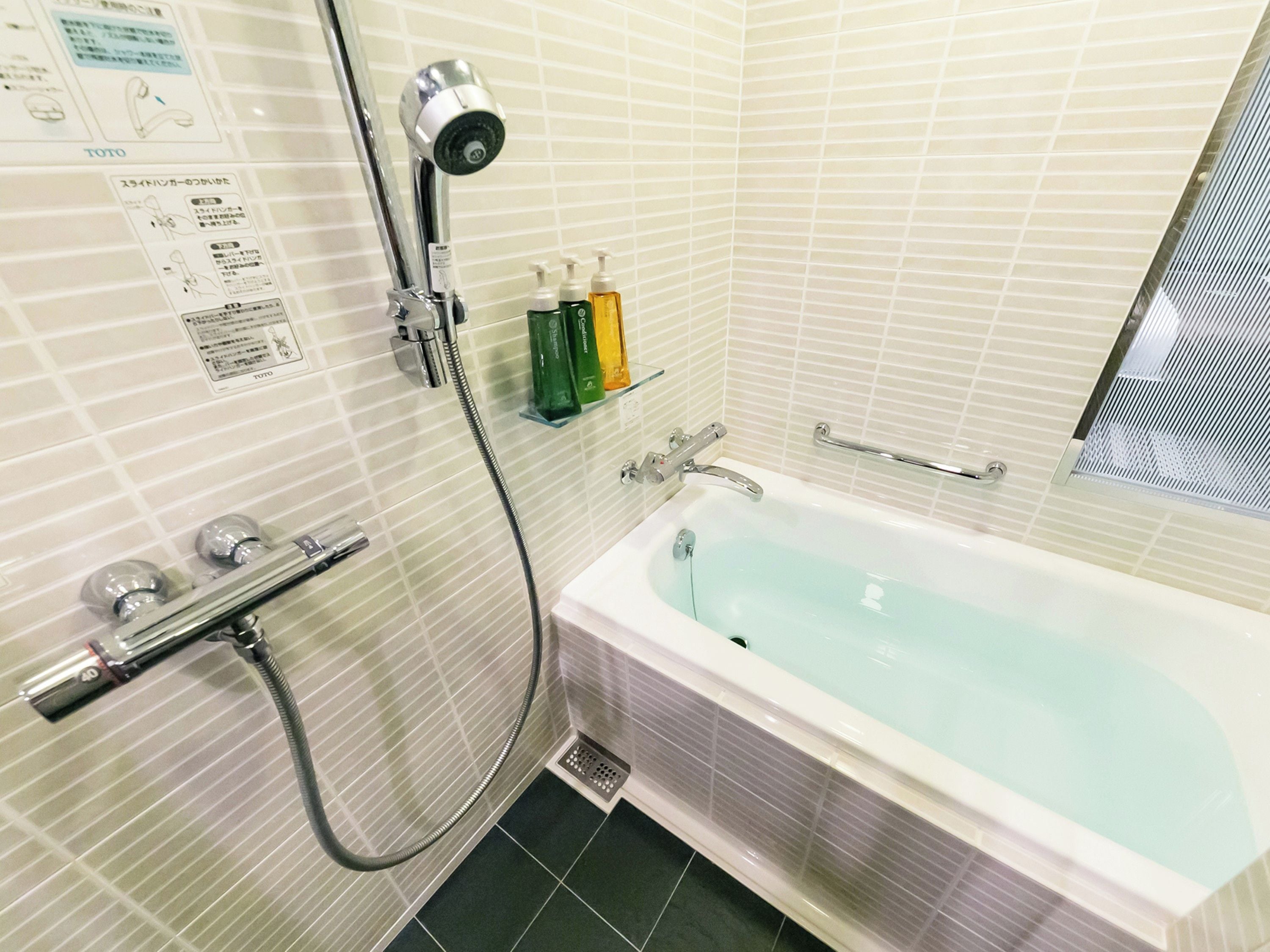 A bathroom with a bathtub, a shower, and a hand dryer.