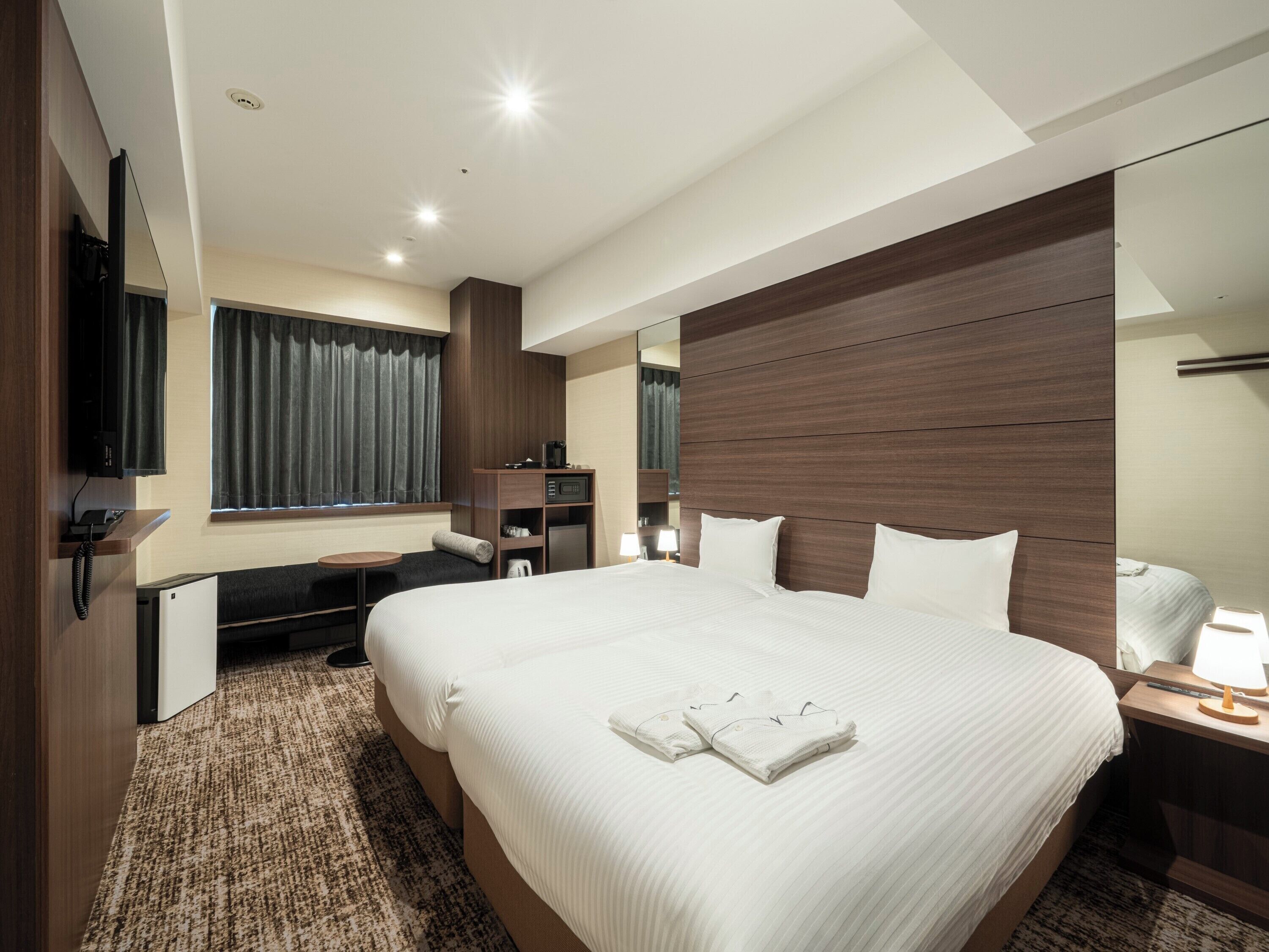 Una habitación de hotel con una cama grande, un escritorio, un televisor y un espejo.