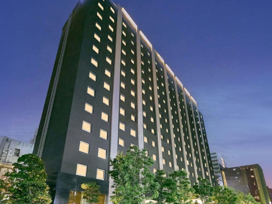 Un hotel alto y moderno con fachada oscura y ventanas regularmente distribuidas.