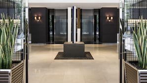 Een moderne lobby met een centrale kolom, glazen wanden en plantenbakken.