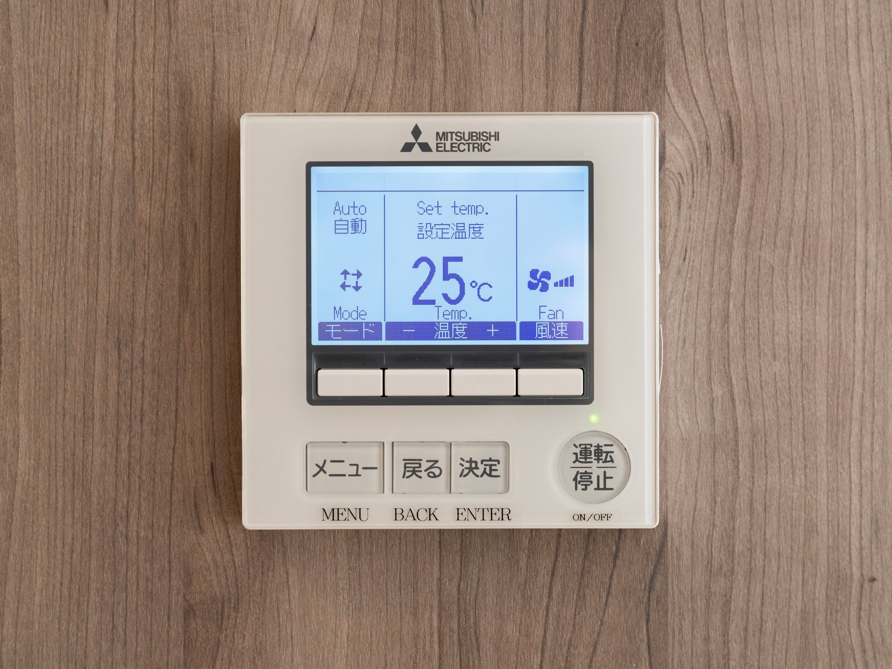 A Mitsubishi Electric air conditioning unit with a digital display, buttons for menu, back, enter, and on/off, and a temperature setting of 25°C.