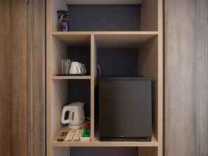 Un espace de rangement bien organisé, avec des étagères contenant une bouilloire, un vaporisateur et quelques livres.