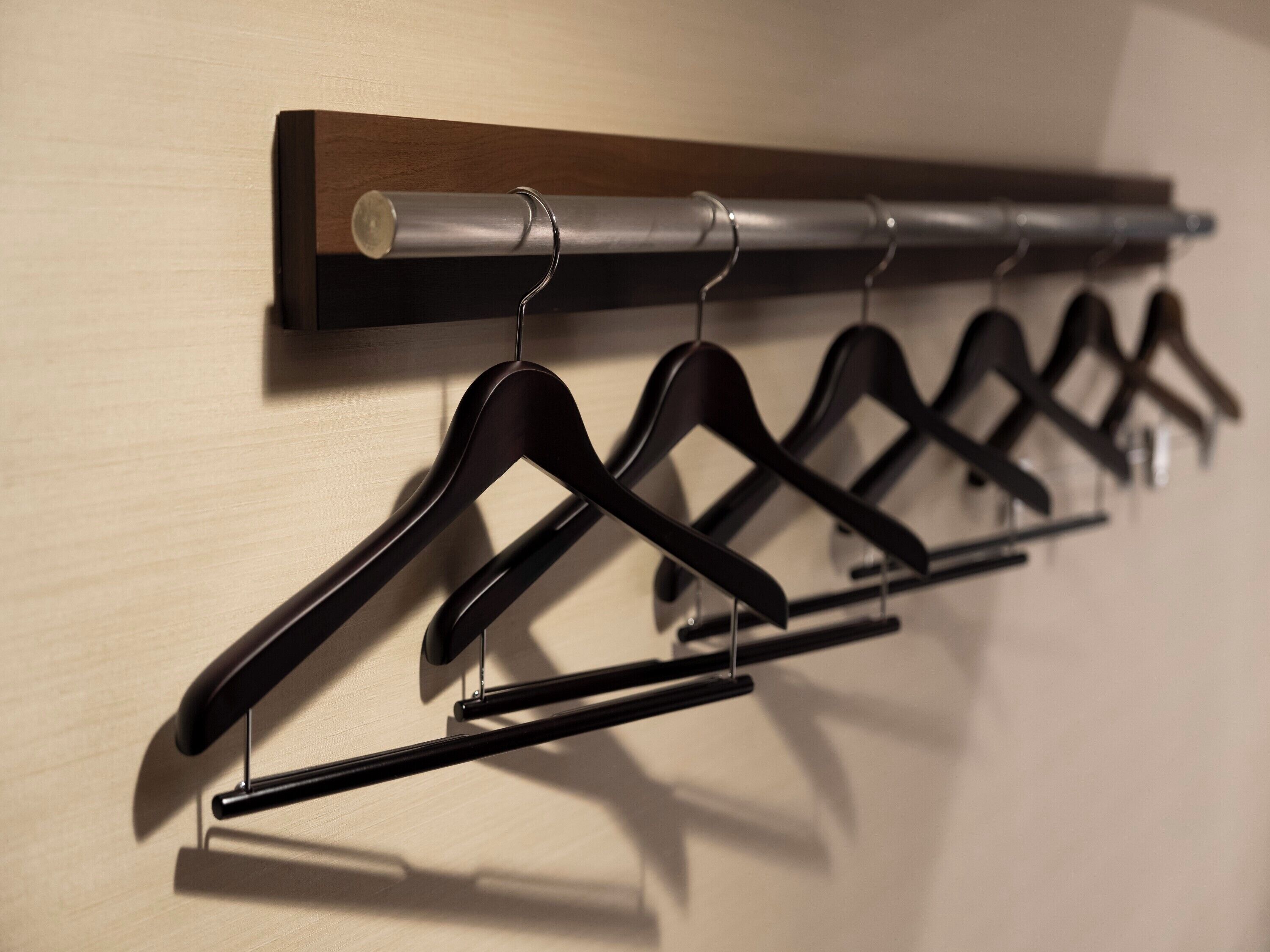A wall-mounted rack with multiple black hangers.