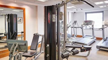 Una palestra con diverse attrezzature per l'allenamento, tra cui un tapis roulant, macchinari per pesi e una panca.