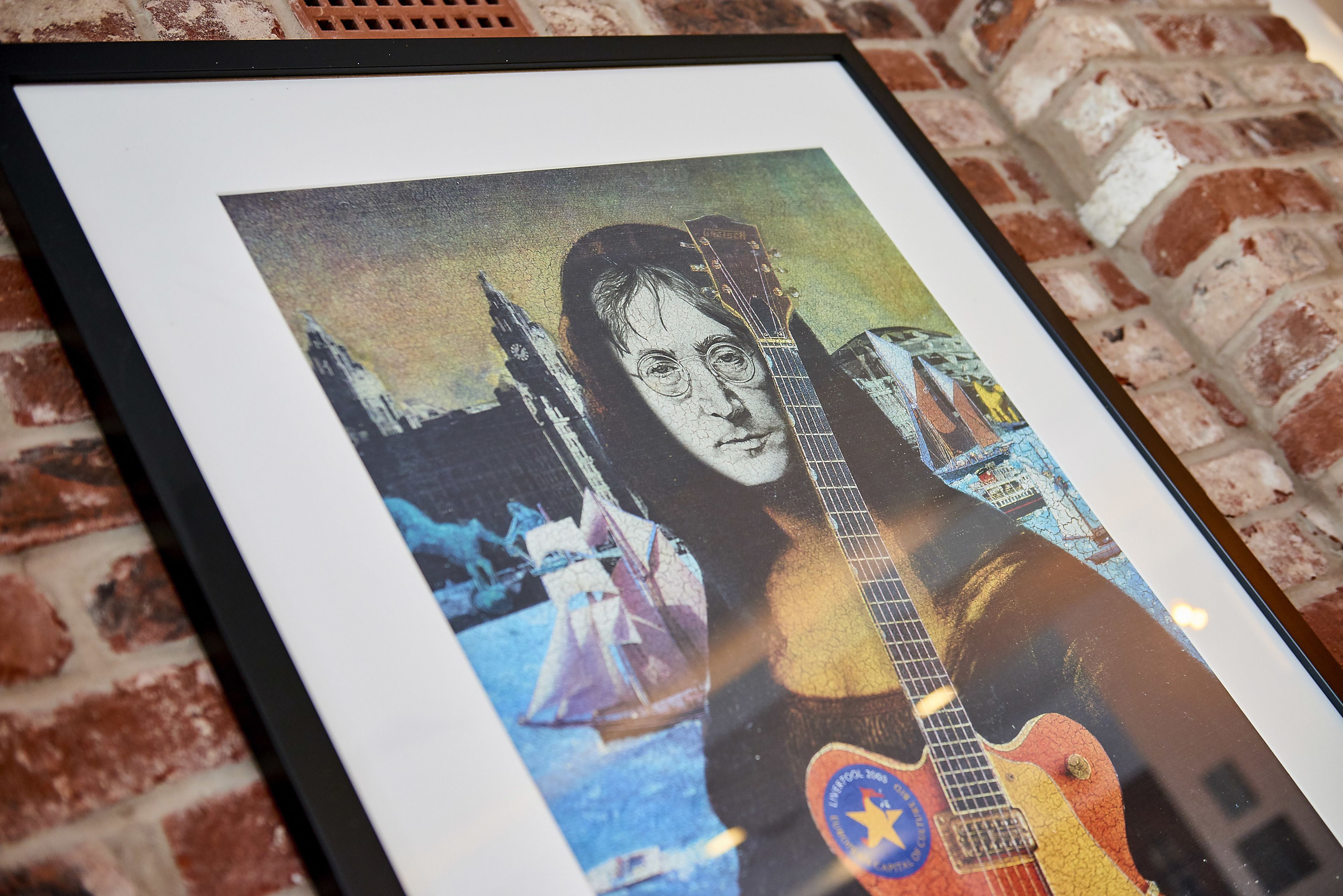 A framed artwork with a guitar, a star, and a cityscape.