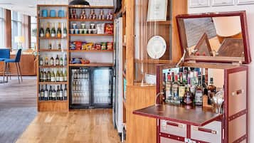 Un espace bar avec des étagères remplies de bouteilles, des en-cas et un réfrigérateur.