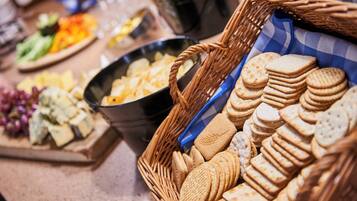 Mesa de buffet com diversos alimentos, incluindo queijo, biscoitos e frutas.