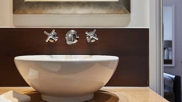 Un lavabo blanco con grifo cromado, sobre una encimera marrón y un panel de madera encima.