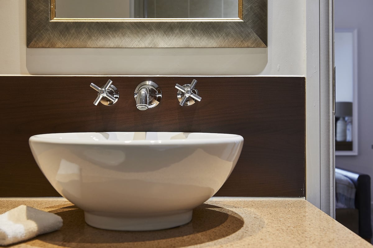 Un lavabo de cerámica blanca con dos grifos de cromo en un baño.