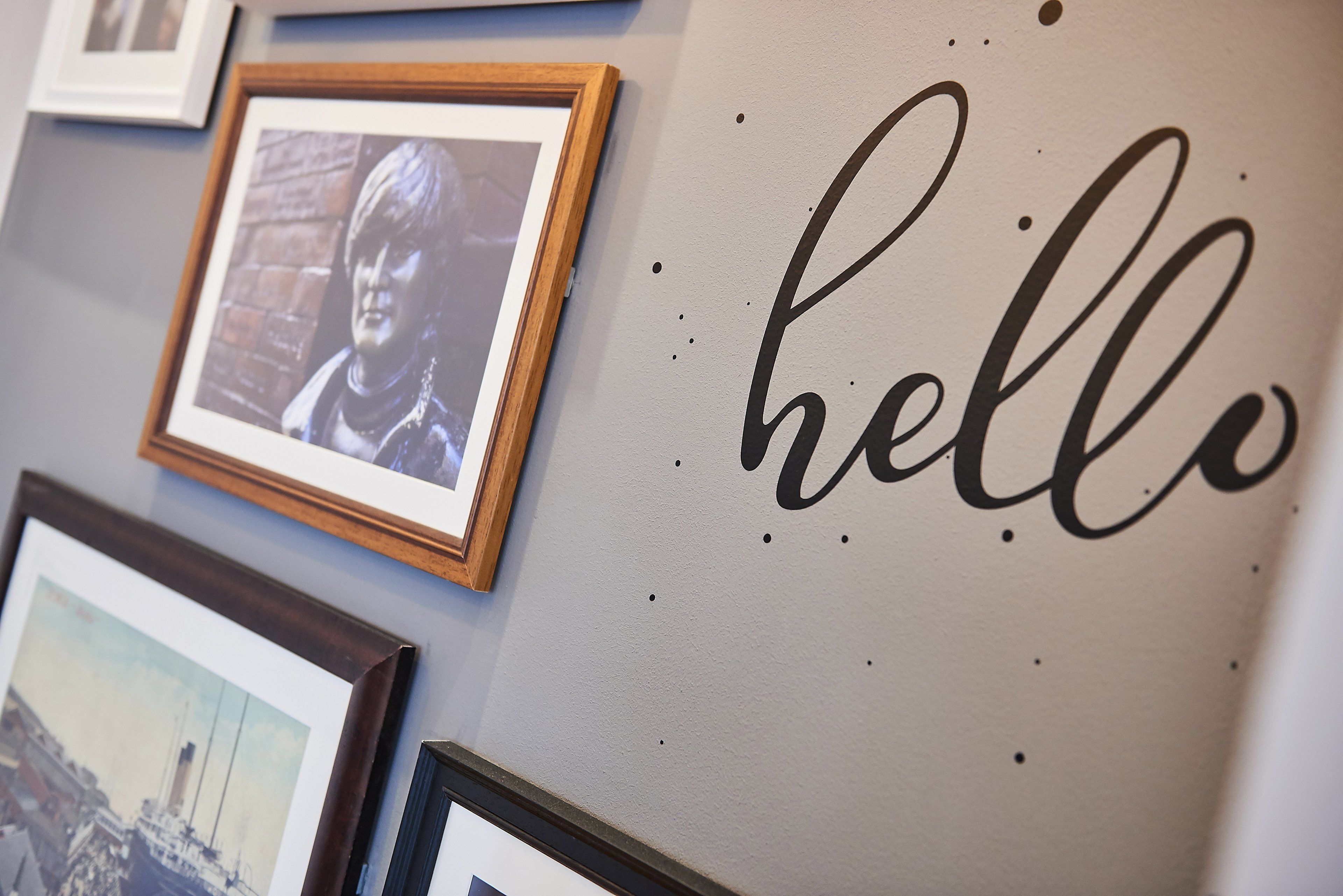 A wall with framed photographs and a 'hello' sign.