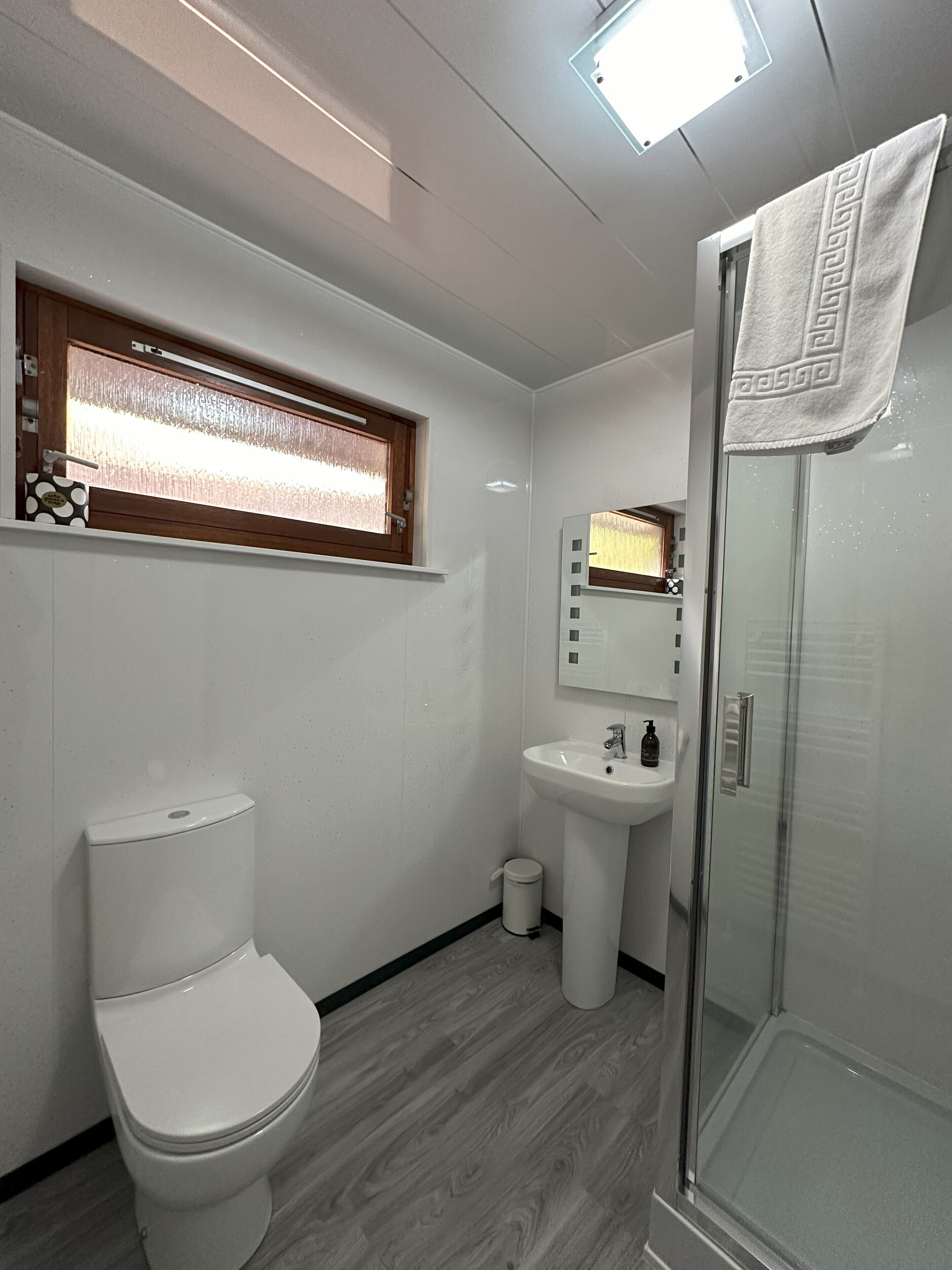 Un baño moderno con inodoro, lavabo y cabina de ducha de vidrio.