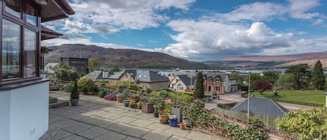 A residential area with houses, a paved walkway, and a mountain in the background.