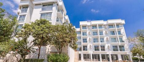 Un hôtel doté d’une piscine, de plusieurs balcons et offrant une vue sur un ciel dégagé.