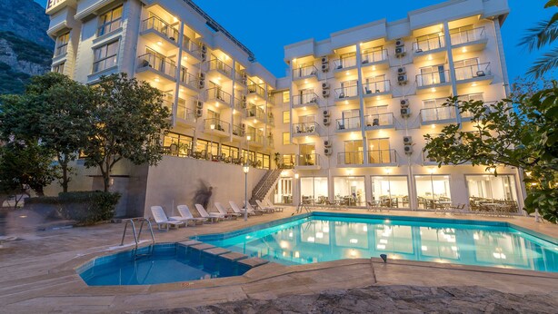 A hotel with multiple balconies, a swimming pool, and outdoor seating areas. - Ekici Hotel (Kas)