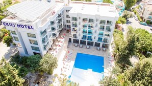 A multi-story hotel with a rooftop pool, balconies, and a courtyard with lounge chairs. - Ekici Hotel (Kas)