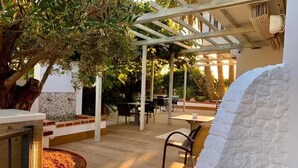 An outdoor patio area with wooden flooring, white stone walls, and a pergola structure. - Hotel Lux isla (Ibiza Town)