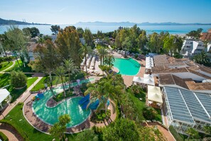 A resort with a large swimming pool, palm trees, and a view of the sea. - Iberostar Waves Ciudad Blanca (Alcúdia)
