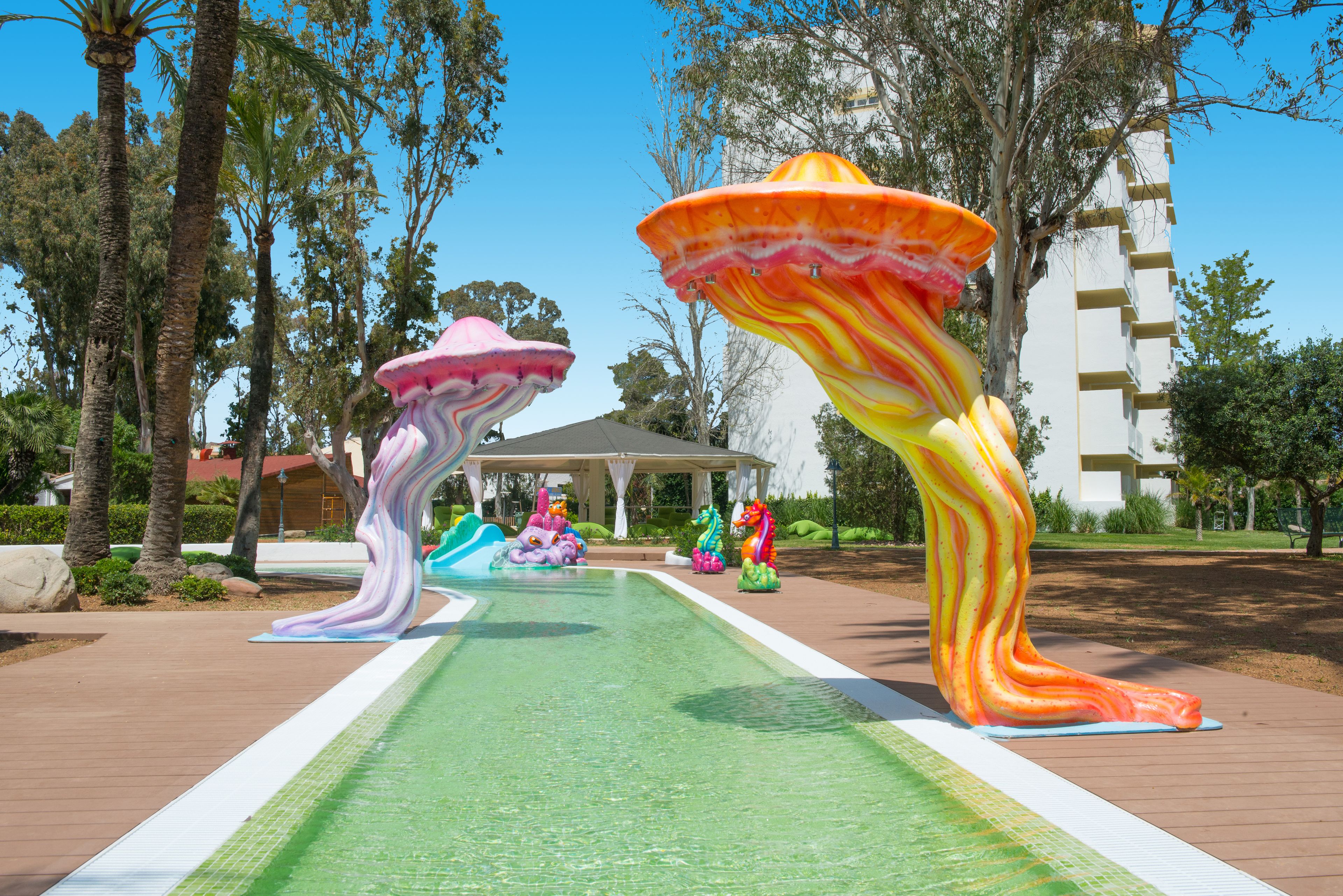 A pool area with colorful mushroom-shaped sculptures and a gazebo in the background.