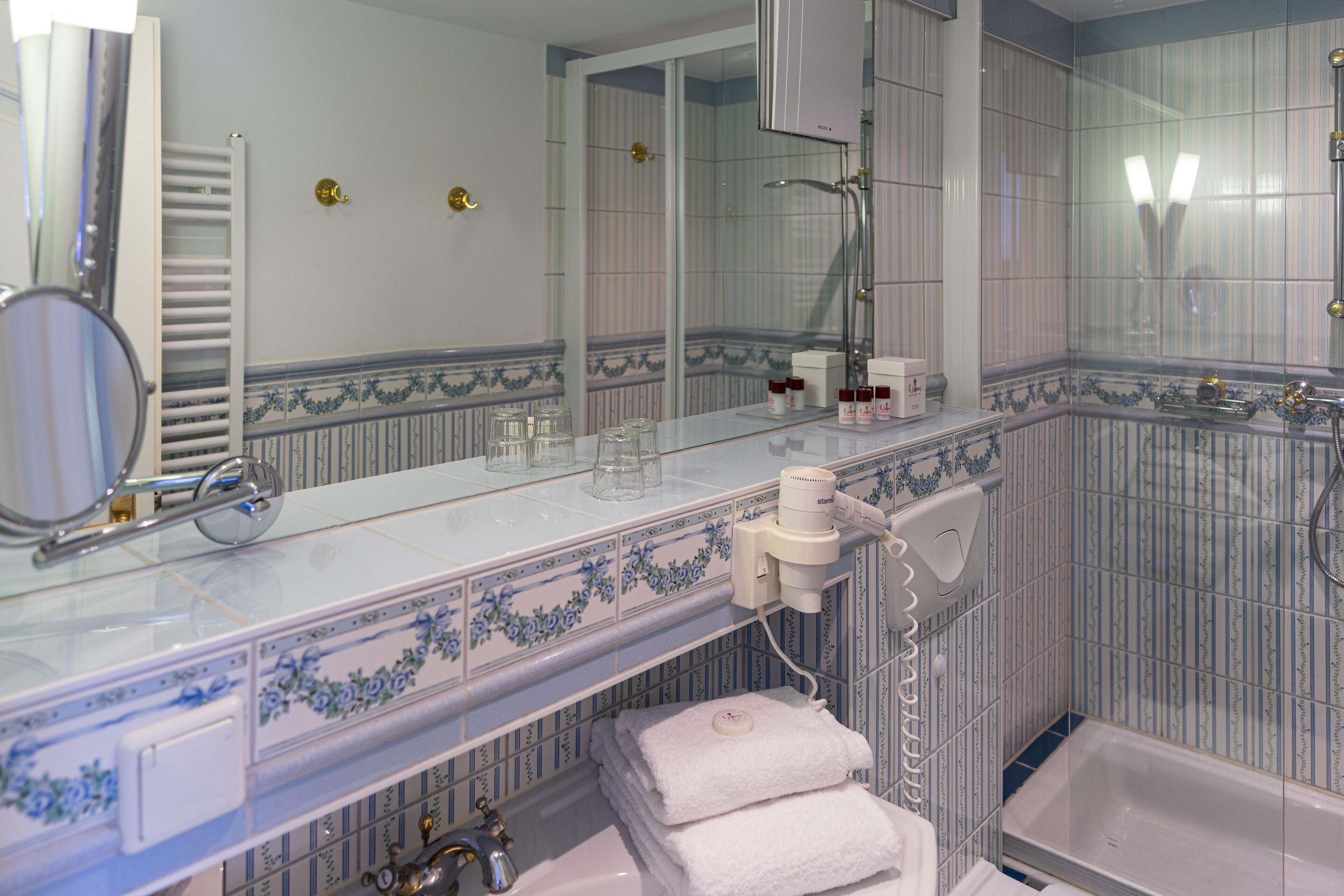 A bathroom with a large mirror, a towel rack, a sink, and a shower area.