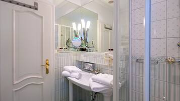 Une salle de bain avec un lavabo blanc, un miroir et un espace douche.