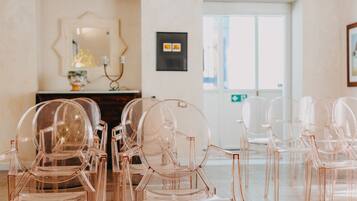 A room with clear plastic chairs arranged in rows, a wooden cabinet with a mirror, and framed artwork on the wall.