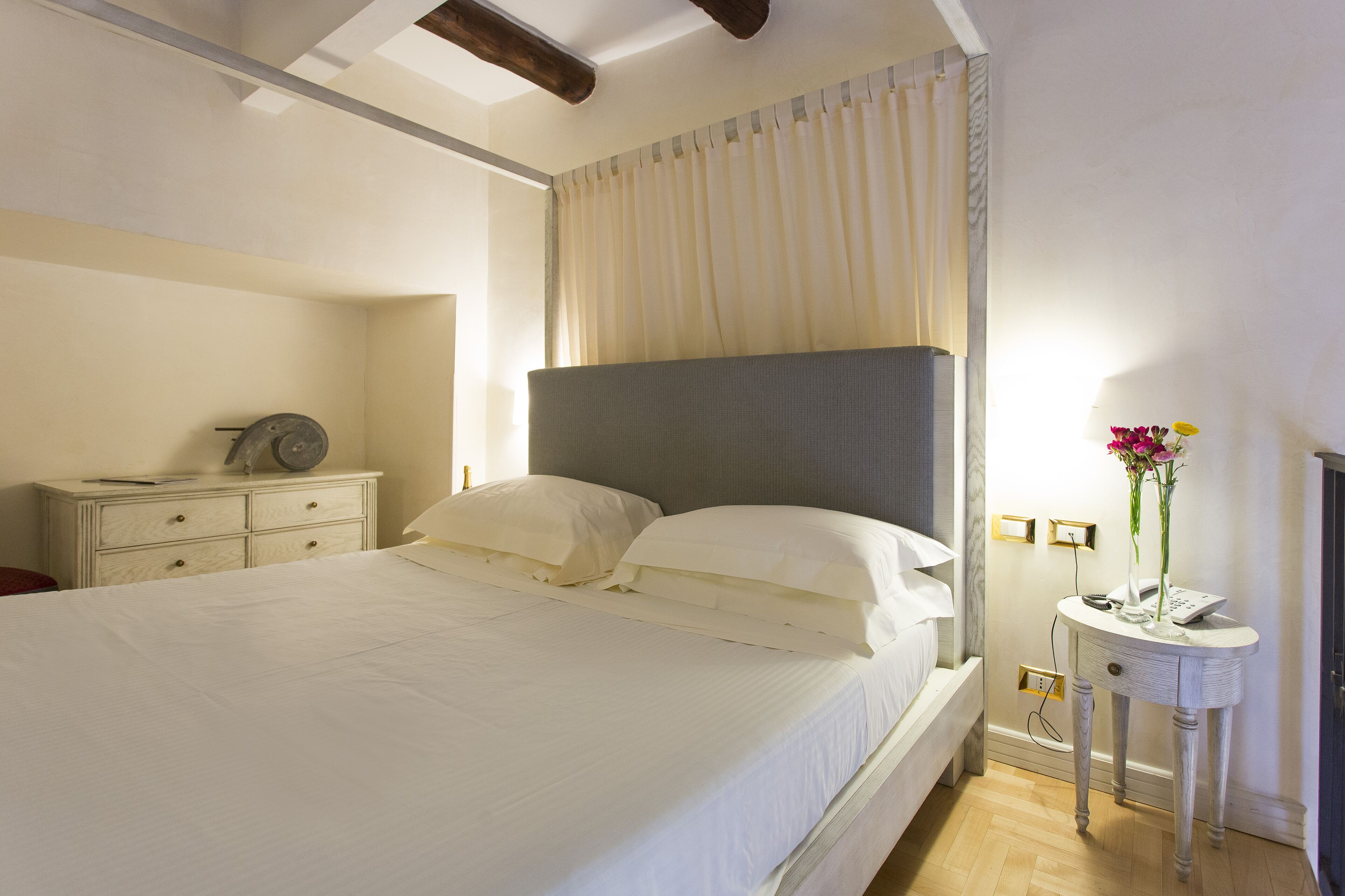 Een slaapkamer met een groot bed, een nachtkastje met een lamp en een nachttafel.