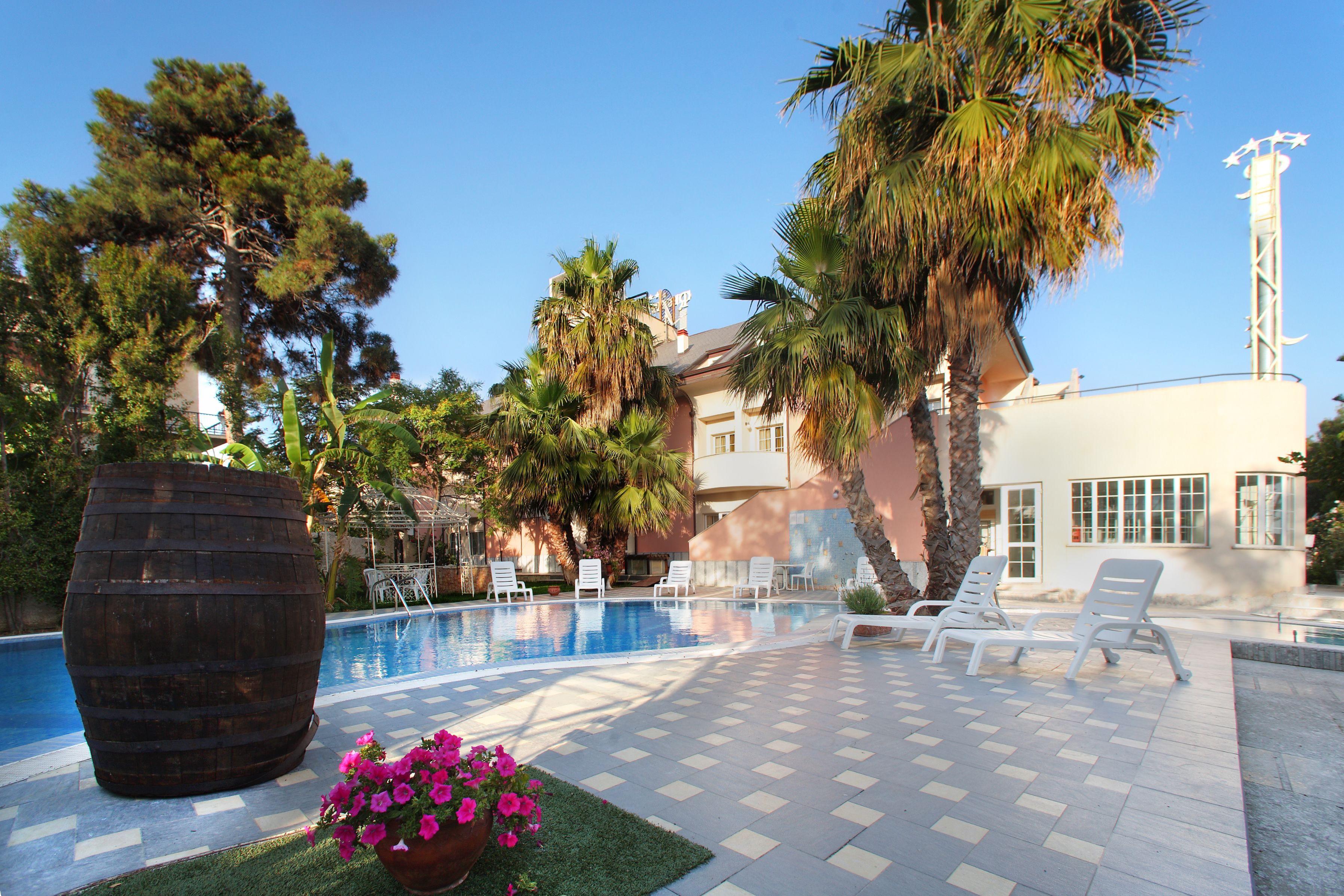 A pool area with lounge chairs, a large planter with flowers, and palm trees.