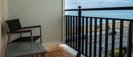 Ein Balkon mit Meerblick, einem Stuhl und einem Tisch.