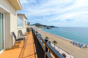 Un balcon avec des chaises et une vue sur une plage parsemée de parasols.