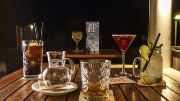Een tafel met diverse drankjes, waaronder een hoog glas met een citroenpartje, een karaf, een glas met een limoen en een cocktailglas.