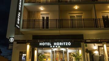 Um hotel de vários andares com uma entrada marcante, varandas e fachada bem iluminada.