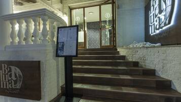 A staircase leading to a restaurant entrance with a signboard and a decorative balustrade.