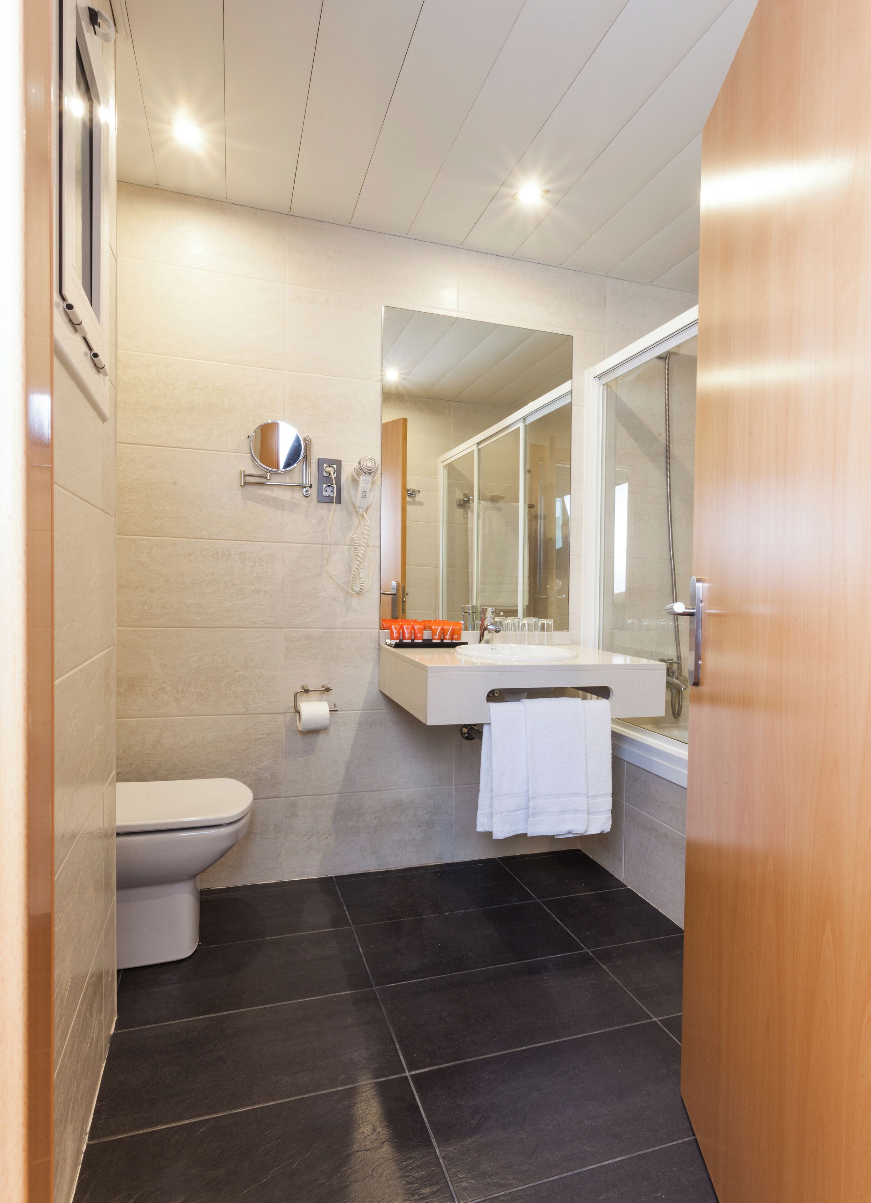 Un baño moderno con inodoro, lavamanos y ducha.
