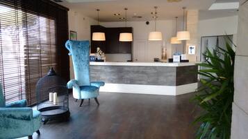 A reception area with a large blue chair, a birdcage, and a reception desk with pendant lighting.
