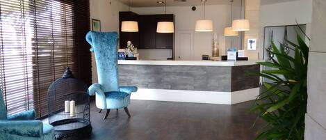 A reception area with a large blue chair, a birdcage, and a reception desk with pendant lighting.