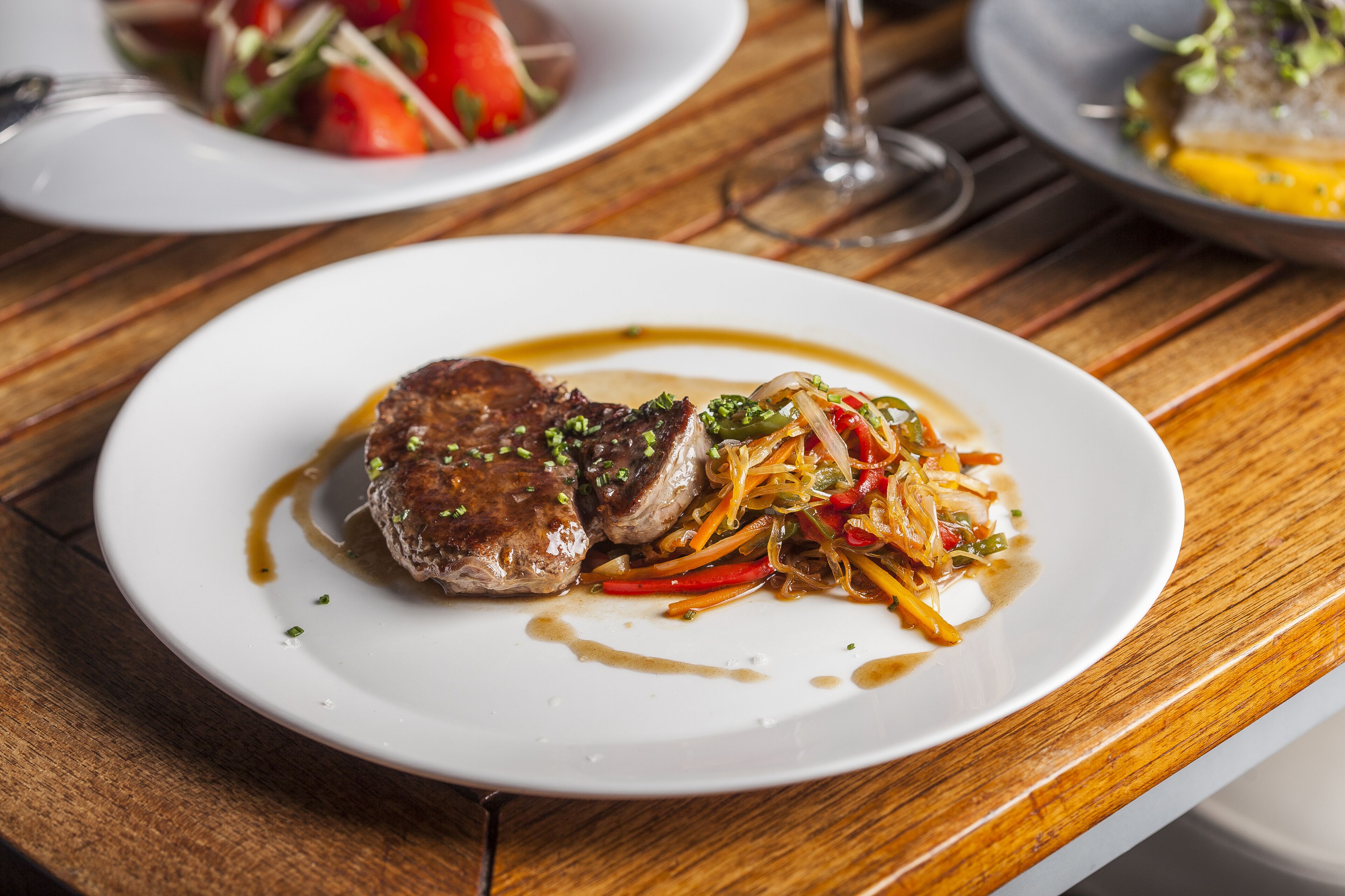 A plate of food with a steak and vegetables on a wooden table.