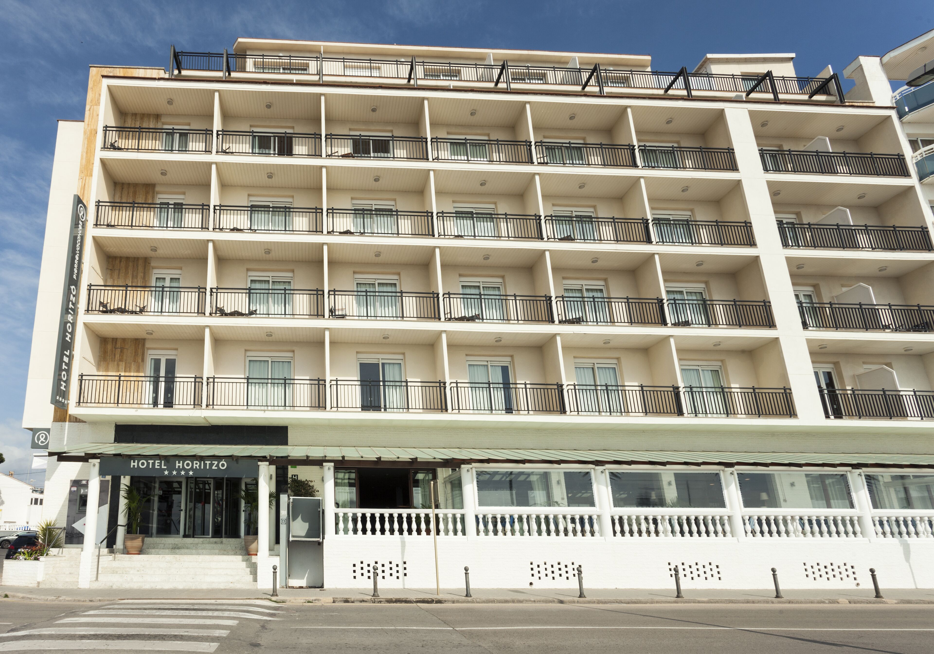 Un hotel de varios pisos con balcones y entrada principal a nivel de calle.