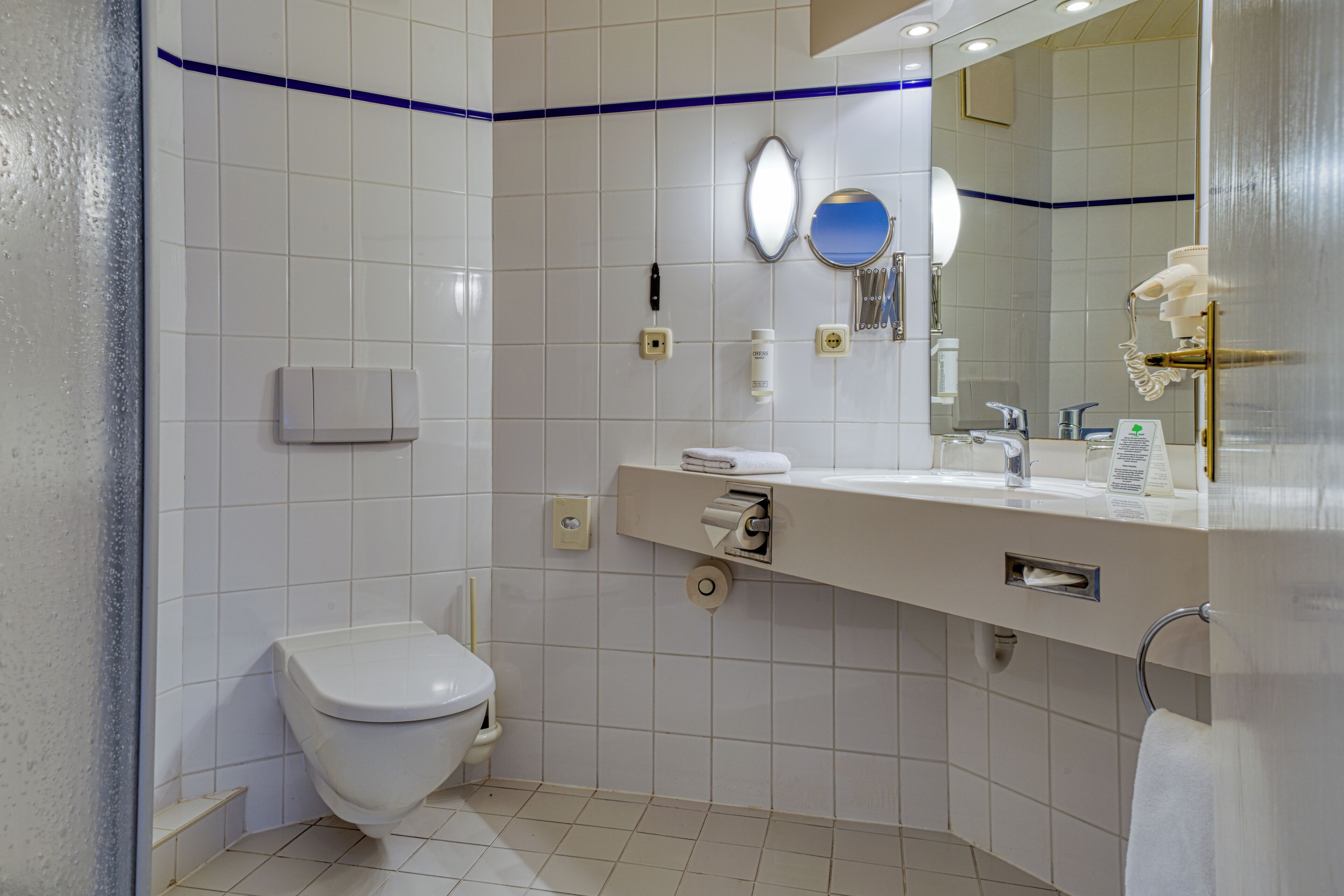Un baño moderno con inodoro, lavamanos y espejo.