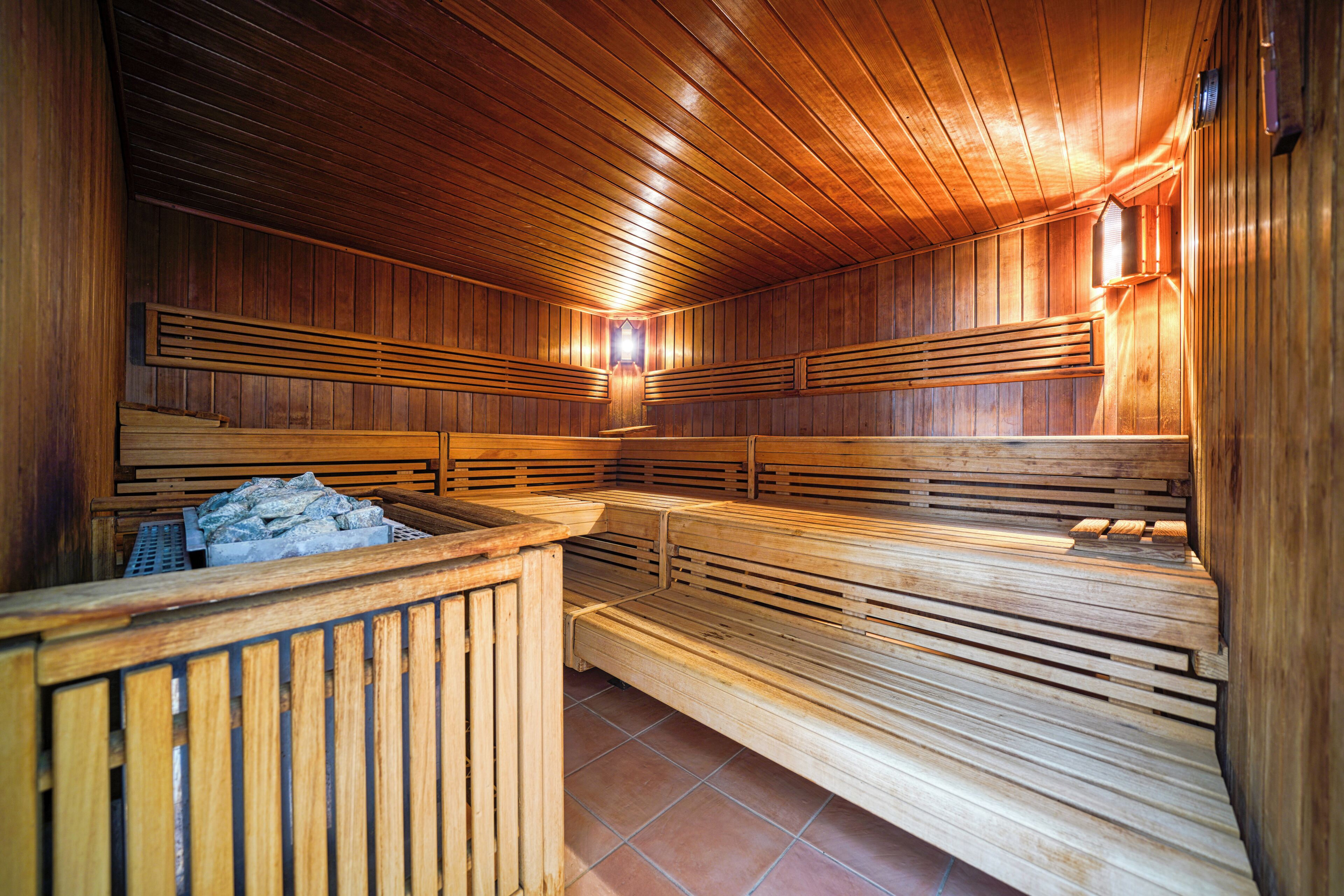 Una sauna con bancos de madera y un banco de piedra.
