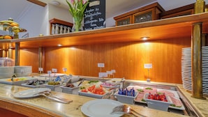 Een buffet met verschillende thematafels, waaronder fruit, salades en vlees.