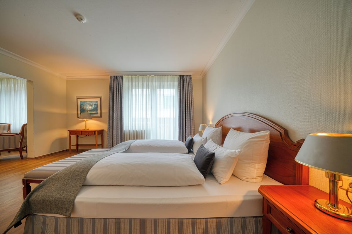 Une chambre d’hôtel avec un grand lit, une table de chevet avec une lampe, une chaise et un tableau au mur.