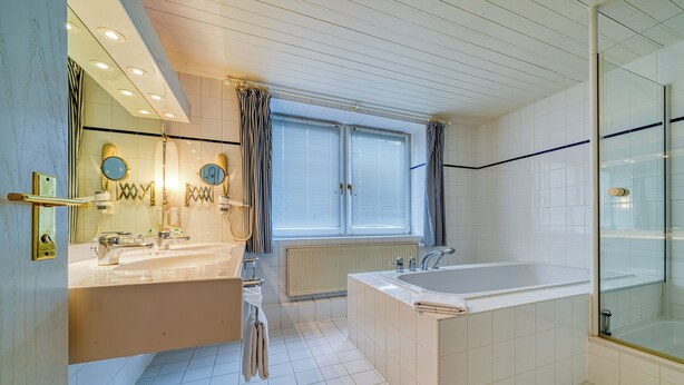 Een moderne badkamer met een ruime badkuip, een dubbele wastafel en een douchecabine met glazen wanden.