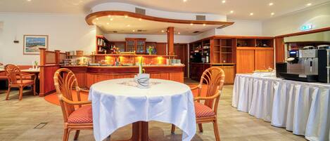 A dining area with a round table, chairs, a bar, and kitchen cabinets.