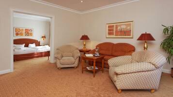 A hotel room with a bed, two armchairs, a small table, and two lamps.