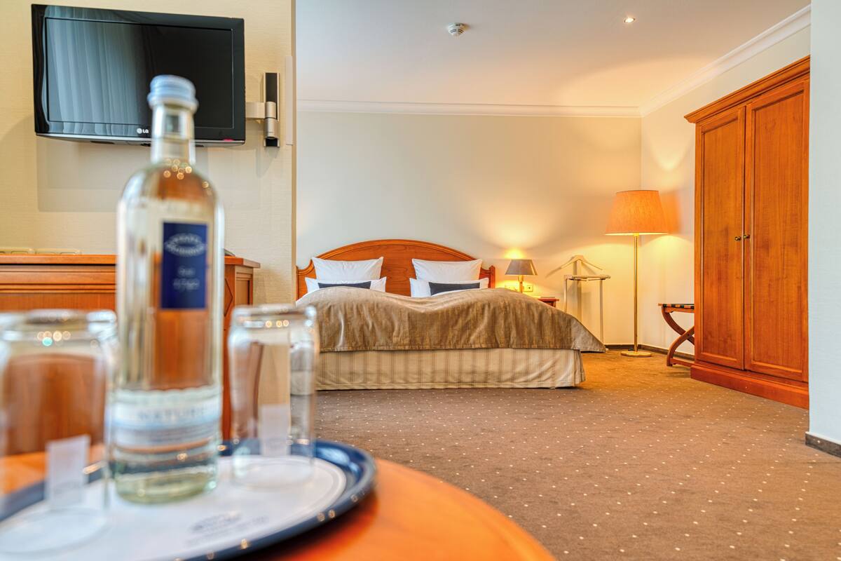 Une chambre d’hôtel équipée d’un lit, de tables de chevet, d’un téléviseur fixé au mur et d’une armoire en bois.