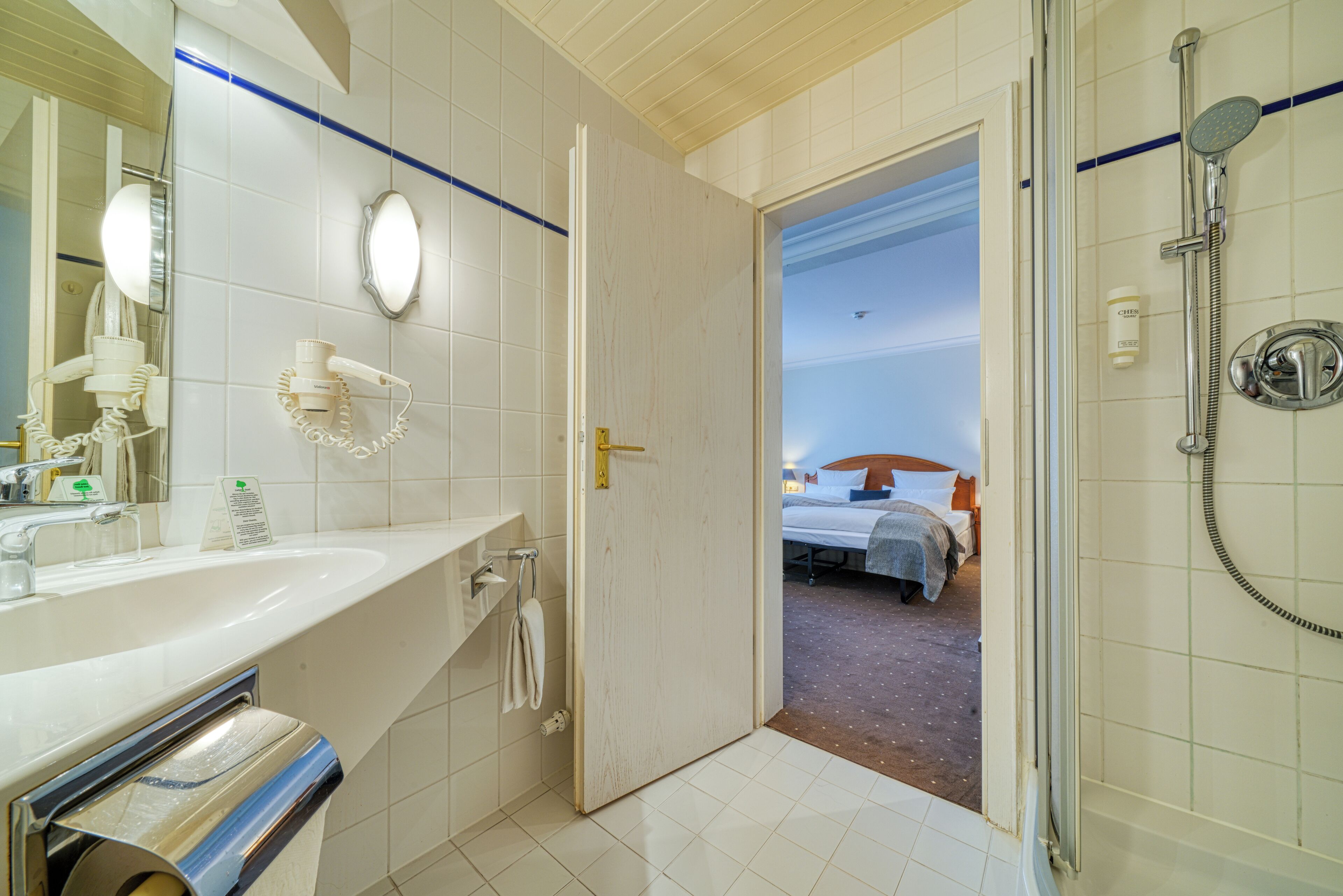 A hotel bathroom with a sink, mirror, and shower.