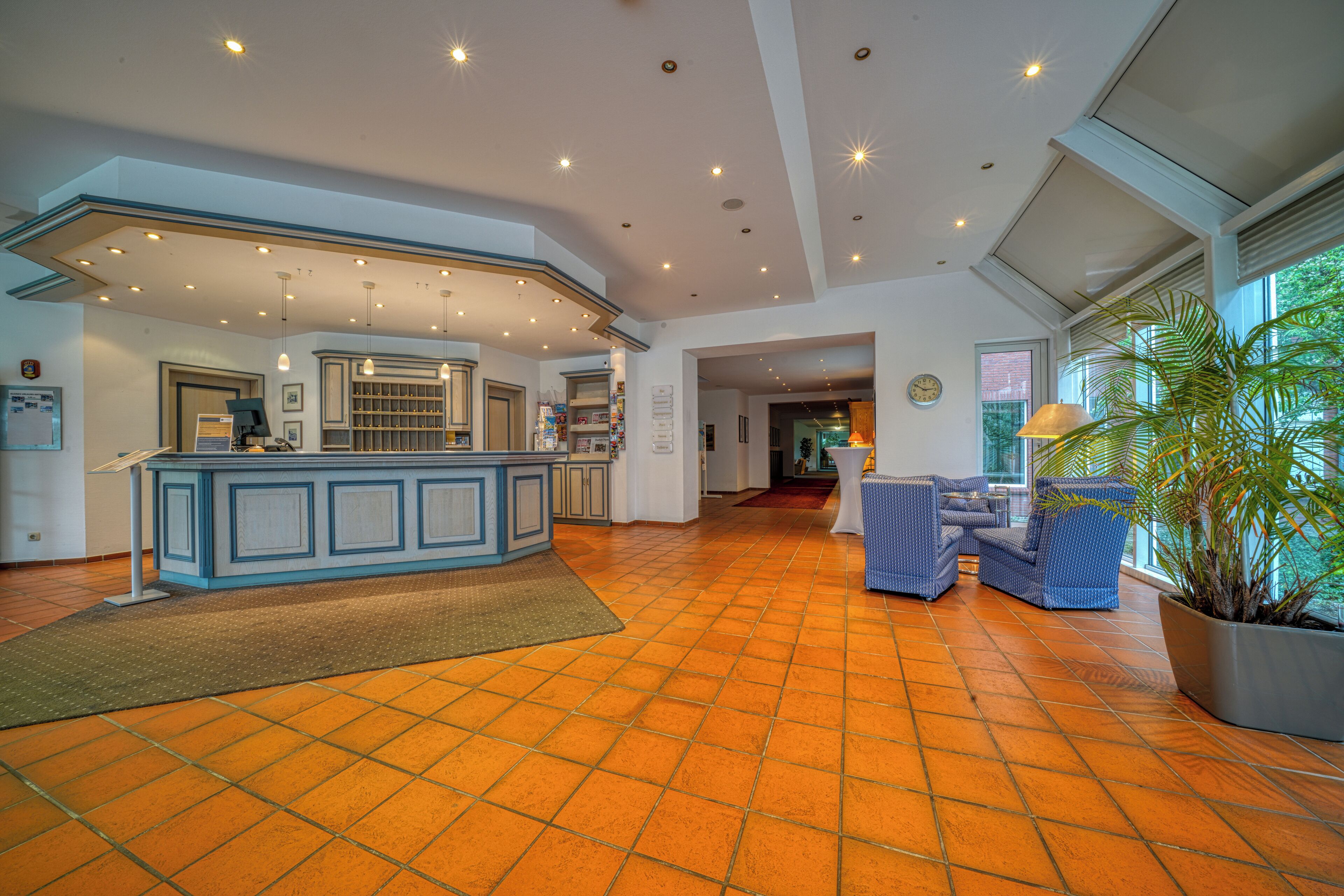 A spacious lobby with a reception desk, seating area, and large windows.
