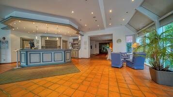 A spacious lobby with a reception desk, seating area, and large windows.