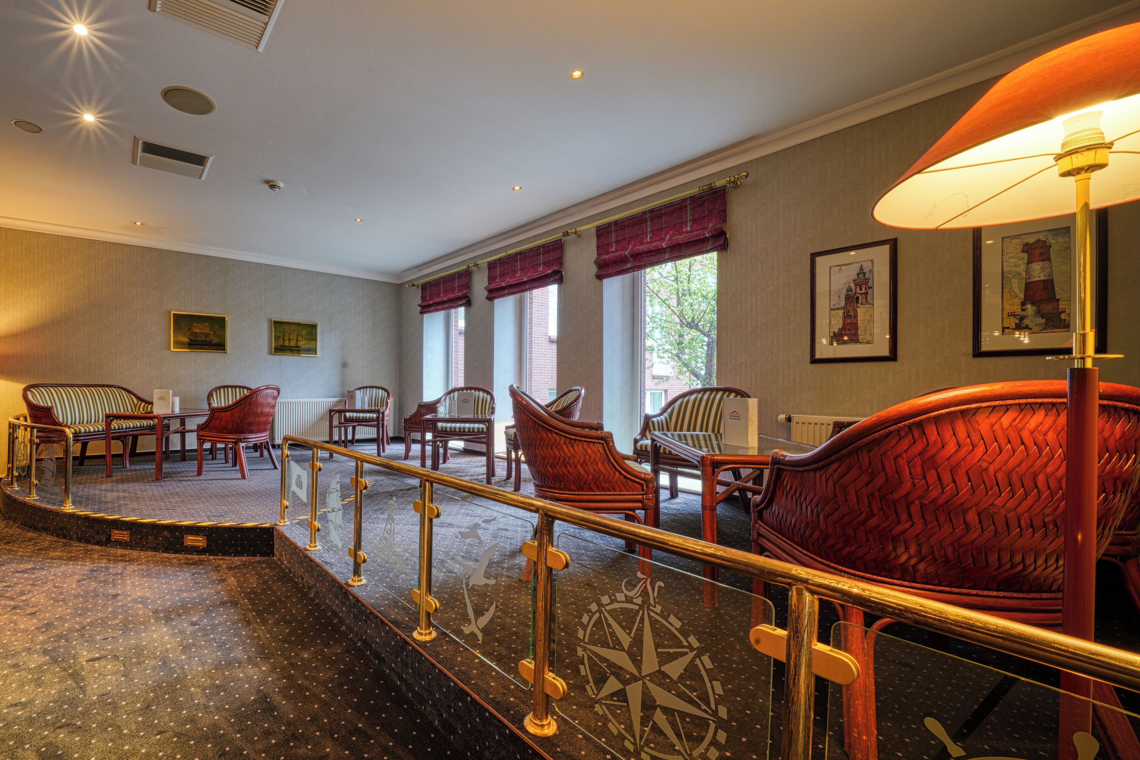 A hotel lobby with a carpeted staircase, wooden chairs, and a large red chair.